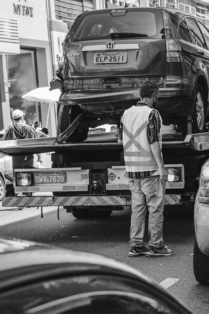 creative Grayscale image of a tow truck loading a vehicle on a busy street in São Paulo.