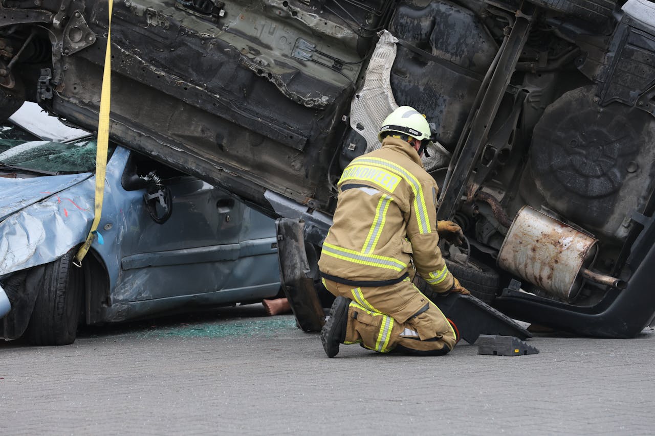 Services-02 Firefighter in gear assisting at an overturned car crash scene, ensuring safety during the rescue operation.